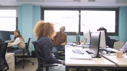 Colegas multiétnicos felizes discutindo e trabalhando em computadores em um espaço de trabalho criativo
