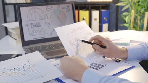Office Worker Analyzes Graphs and Charts in Office