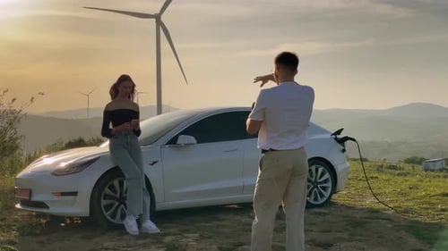 Una impresionante sesión de fotos de un vehículo eléctrico tomada durante la puesta de sol junto a una turbina eólica