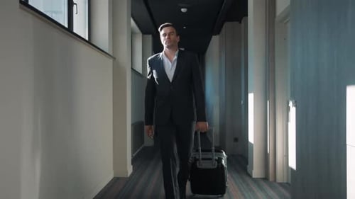 Successful businessman arriving at business hotel walking through the corridor