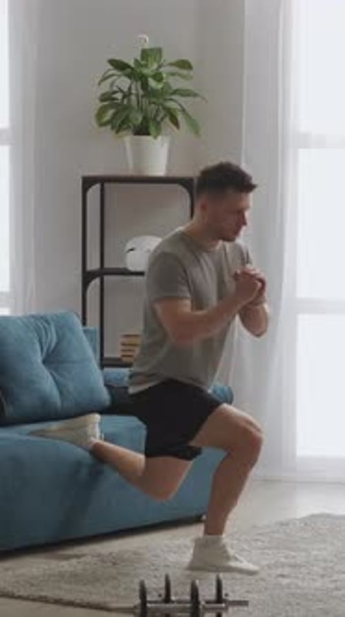 Young Man Performing Singleleg Lunge Exercise Using Living Room Sofa for Support Focusing on Balance