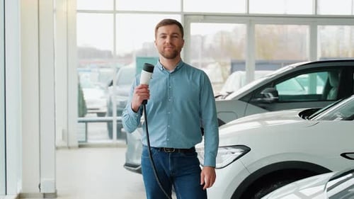 Man Holding Electric Car Charging Plug at Car Dealership