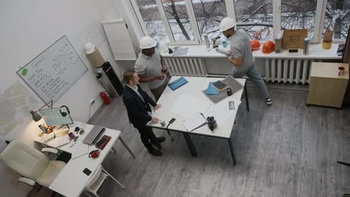 High Angle of Construction Team Analyzing Blueprint at Office Table