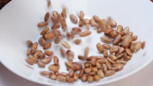 A bowl of roasted peanuts and beans, a common coffee bean staple, with a hand swirling