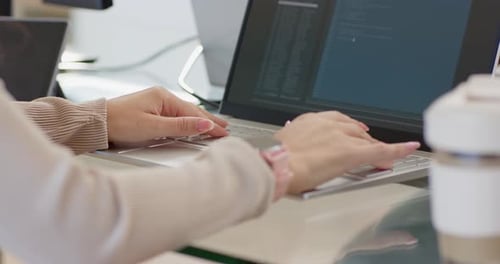 Seeing code editor, female coder typing, tapping touchpad at desk, pointing at laptop, editing code