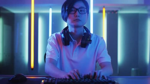Man Uses Computer With Neon Lights in Room