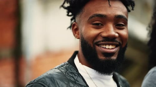Portrait of a joyful black Brazilian young man smiling and laughing in urban environment. Close-up