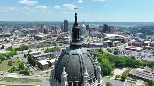 Saint Paul skyline behind St. Paul Cathedral dome. Aerial orbit shot in Minnesota.