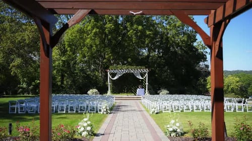 White Wedding Arch with Flowers Decorated Chairs in Park Ceremony on Sunny Day
