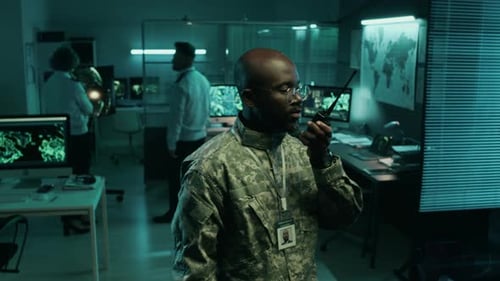 Black Army Commander Transmitting Instructions on Radio in Operations Center