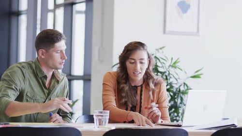 Diverse male and female colleagues in discussion using laptop in casual office meeting