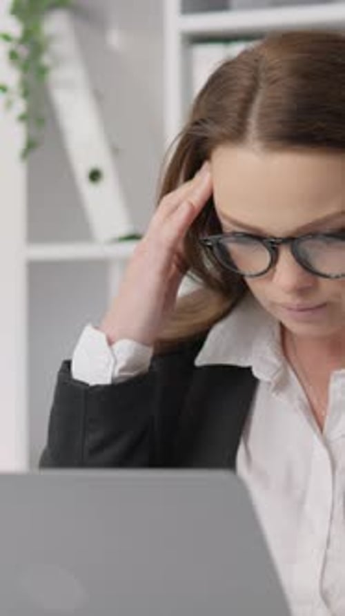 Woman Working On Laptop Massages Temple At Work