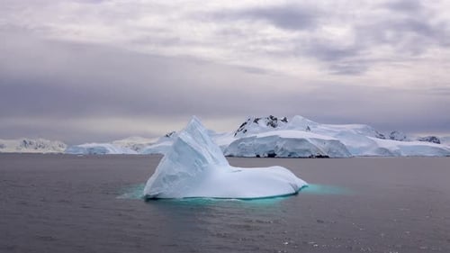 There is a light blue ice floe in the ocean. In the background is a long iceberg.