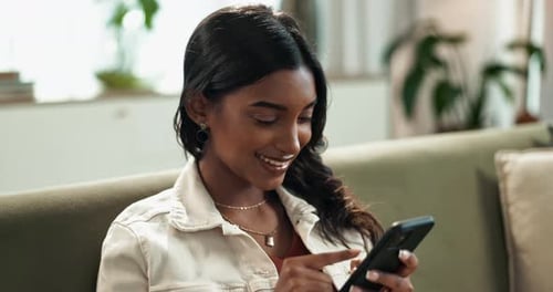 Woman Smiling and Using a Mobile Phone at Home