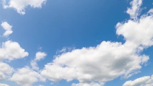 Wind blowing and white clouds quickly change shapes. Sun lighting the cloudscape. Low angle view
