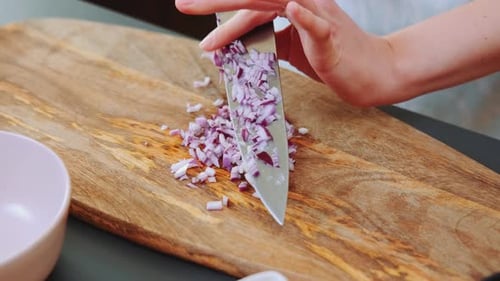 Hands Chopping a Red Onion on Cutting Board