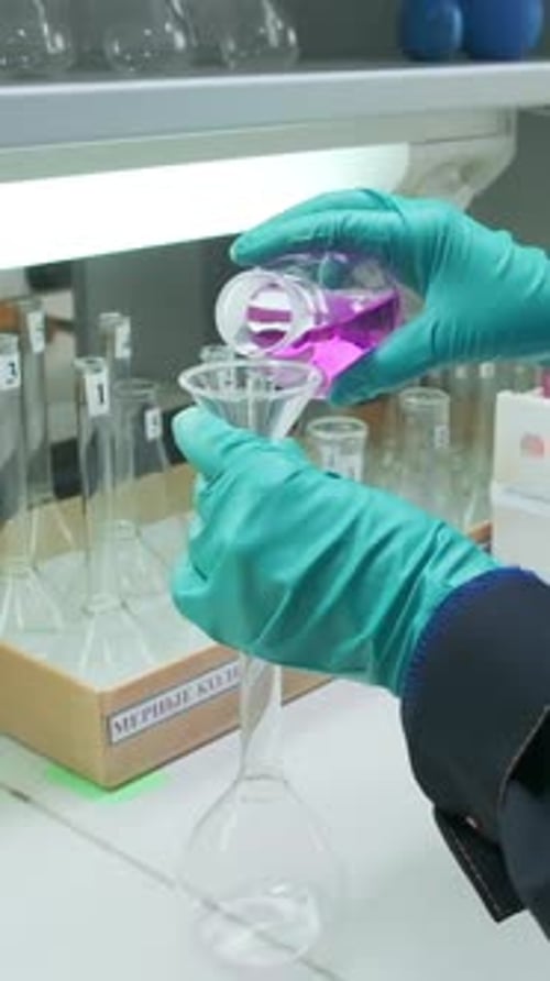 Clip conceptuel de chimie Un homme portant des gants qui teste un liquide rose pour une expérience