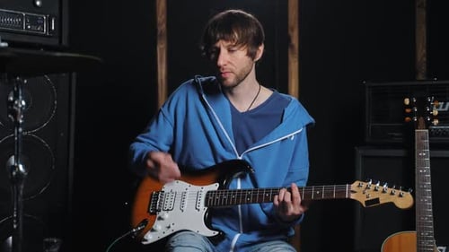 Adult Plays Electric Guitar in Recording Studio