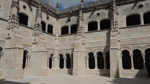 Gothic stone courtyard with intricate arches and windows, shot during daytime