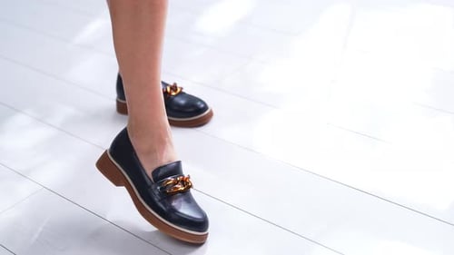Woman Wearing Stylish Black Leather Loafers with Gold Detail