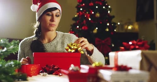 Woman Putting Bow on Christmas Present in Home