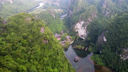 Aerial Flying Over Forested Limestone Valley Mountains Of Ninh Binh With Tilt Down View Of Trang An