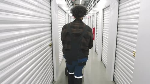 Vue arrière d'un homme marchant le long d'un long couloir blanc dans un entrepôt à climat contrôlé