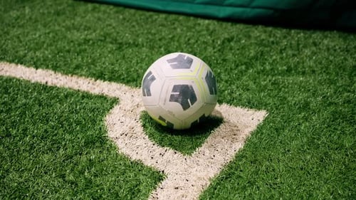 close-up of the ball standing on the corner white line marking on a soccer synthetic grass field