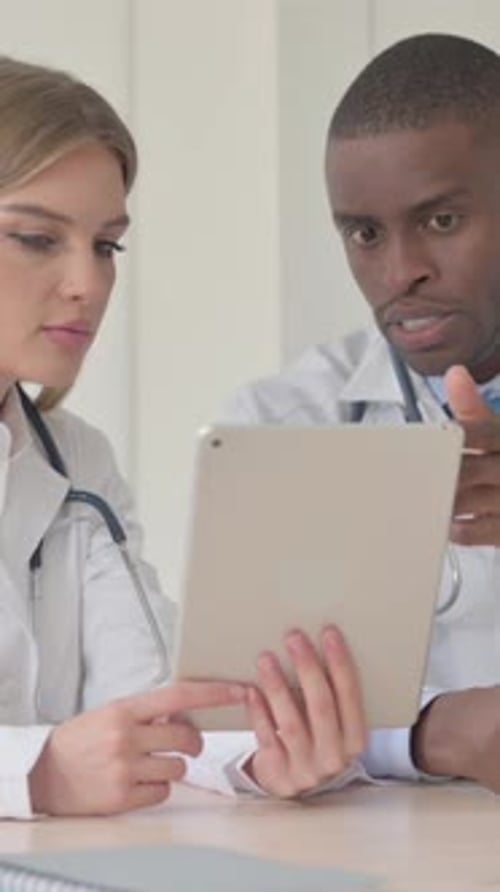 Female Doctor and African Doctor Working in Clinic, Using Tablet, Vertical Video