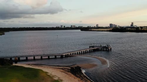 People enjoying a sunset walk along a pier at a riverside in an urban area
