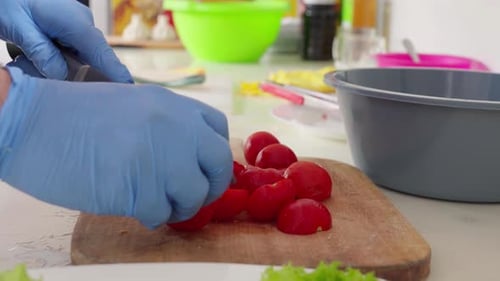 Chef slicing red cherry tomatoes in a restaurant kitchen