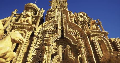 Intricate Stone Structure with Carvings and Animals Under a Clear Sky