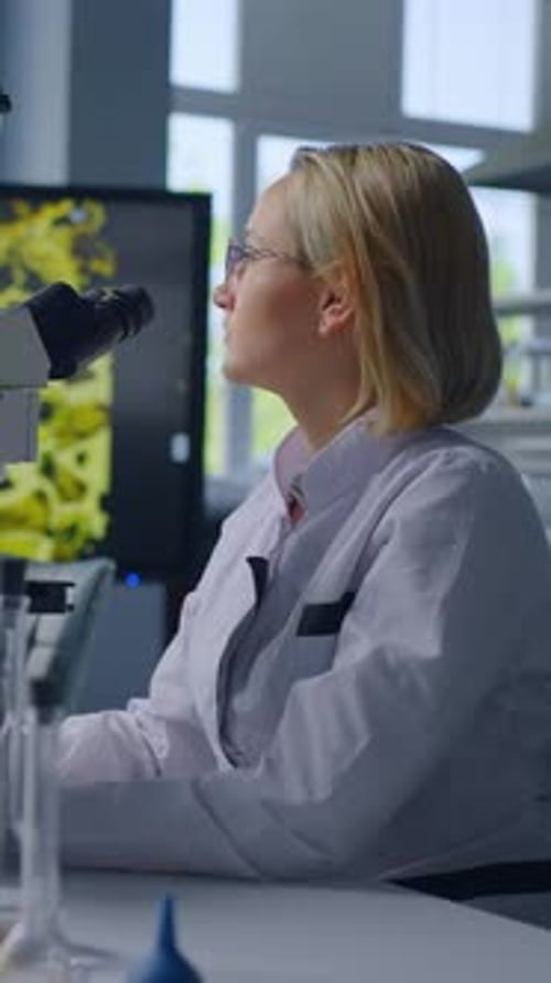 Young Woman Scientist Using Microscope in a Lab