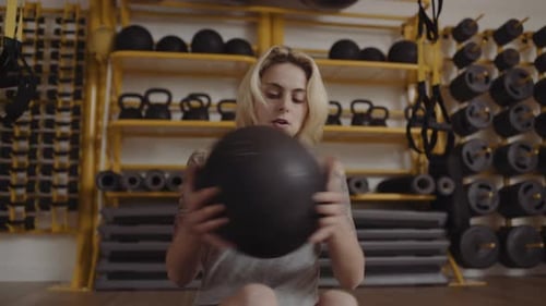 Young woman doing abdominal exercises with ball in gym