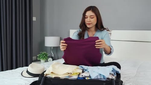 Woman Folding Clothes for Travel in Bedroom