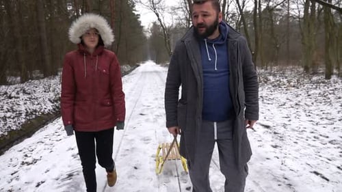 Happy father and daughter walking together in snowy winter forest slow motion