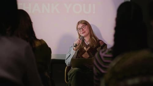 Young Woman Speaking with Microphone during Presentation in Creative Event