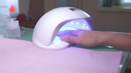 Woman Curing Gel Nails With Blue Light Device
