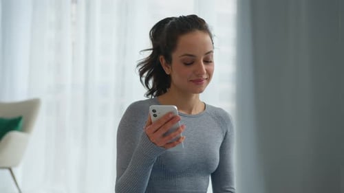 Woman Using Phone and Drinking Water Indoors