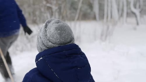 Family Pulling Child on Sled in Winter Forest