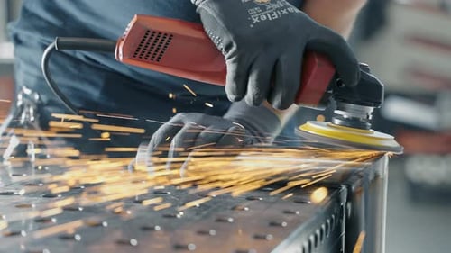 Metal Worker Grinding on Metal Workbench