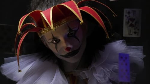 Une farceur effrayante avec du maquillage et un chapeau a l'air avec une expression folle, des cartes à jouer flottent