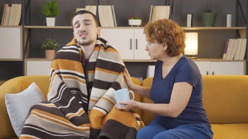 Caring Woman Giving Tea to Sick Young Man