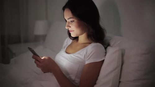 Woman in Bed Using Mobile Phone at Night