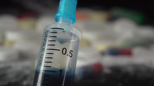 Syringe plunger pushes out blue liquid