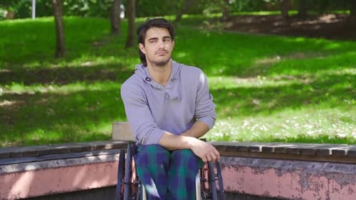 Young Man Sitting in a Wheelchair in Park