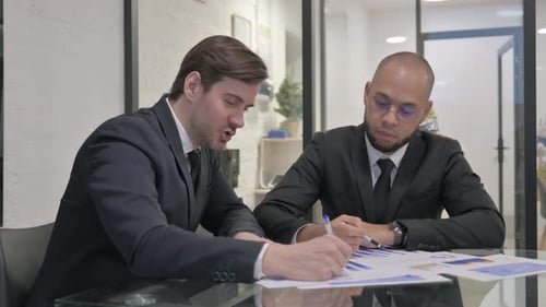 Businessmen Meeting Discussing Graphs in Modern Office