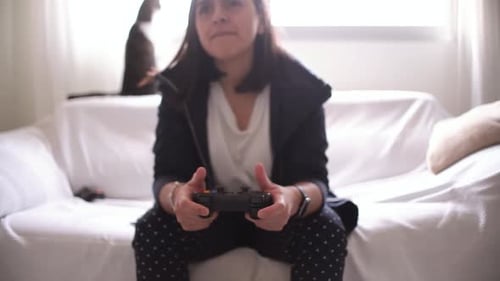 Woman's hands using gamepad close-up view playing video console game at home sitting on the sofa.