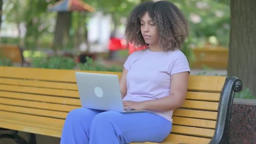 Woman Works On Laptop While Sitting on Park Bench