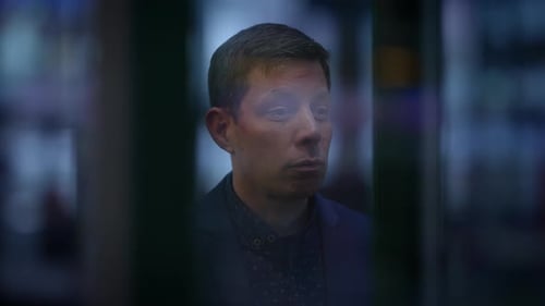 A Man with Glasses in a Pensive Mood Stares Out of a Window Reflecting Silently in the City Night